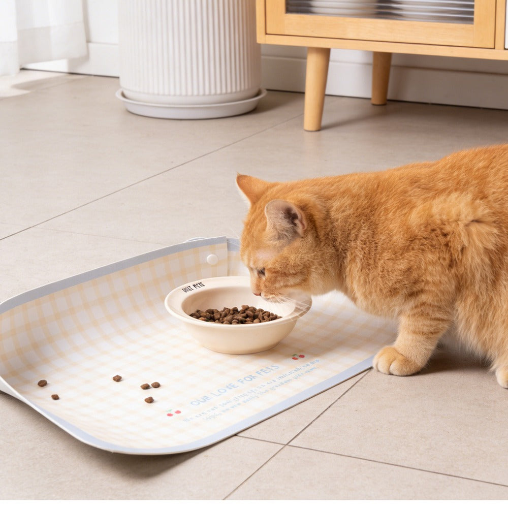 Orange cat eating on an anti-spill gingham pet food mat