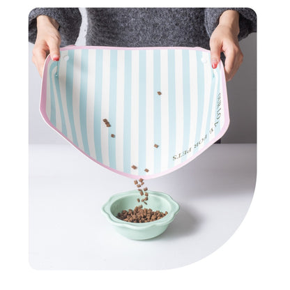 Pouring spilled kibble off the PU leather pet mat into a bowl